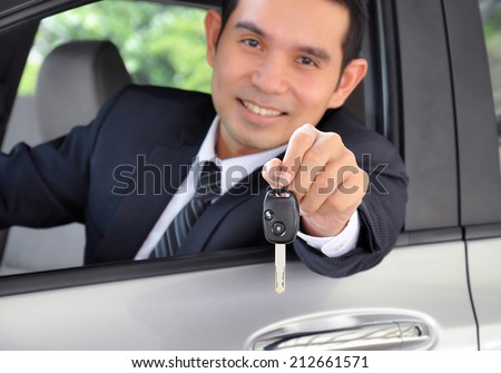 Asian businessman as a driver giving a car key - car sale & rental business concept