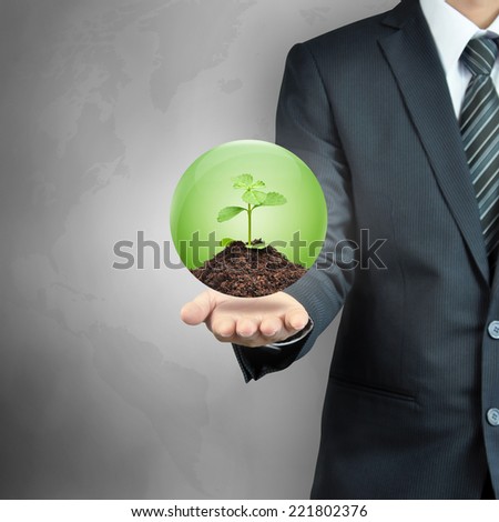Businessman carrying green sapling with soil inside the sphere - sustainable development & nature conservation concept
