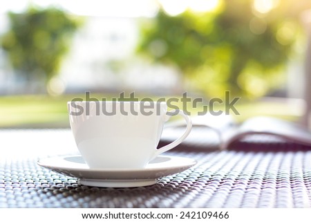 Coffee cup with book on blurred green nature background - chill out concept
