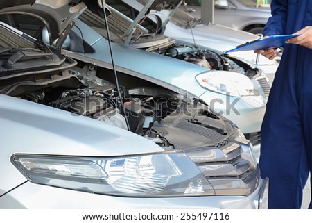 Auto mechanic (or technician) checking car engine at the garage