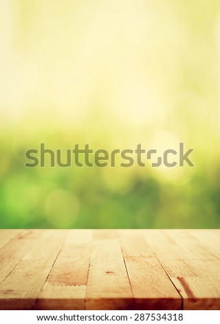 Wood table top on green bokeh abstract background, vintage tone, poster size proportion - can be used for montage or display your products