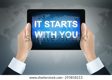 IT START WITH YOU text on tablet pc screen held by businessman hands