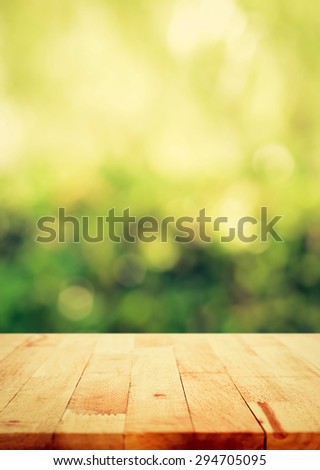 Wood table top on green bokeh abstract background, poster size proportion, vintage tone - can be used for display or montage your products