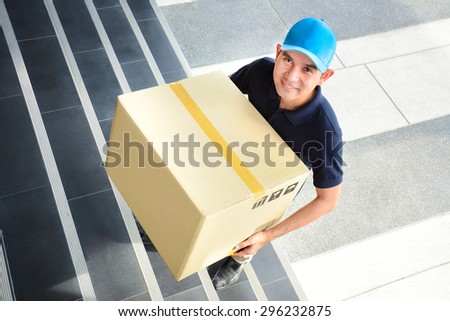 Deliveryman walking up stairs, carrying a big parcel box