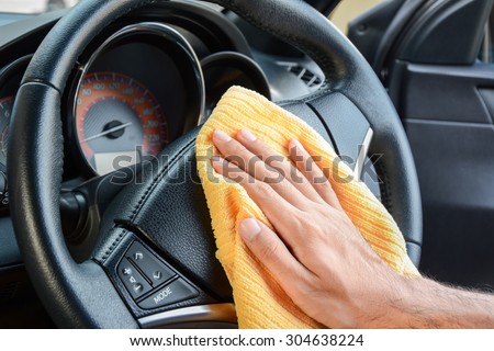 Hand cleaning car steering wheel with microfiber cloth, auto detailing (valeting) concept