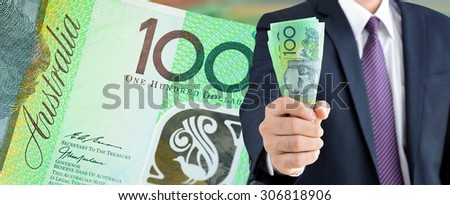 Businessman holding money, Australian dollars (AUD), on 100 banknote background  - financial and investment panorama background concept