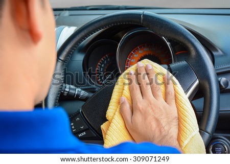 A man cleaning car steering wheel with microfiber cloth, auto detailing (valeting) concept