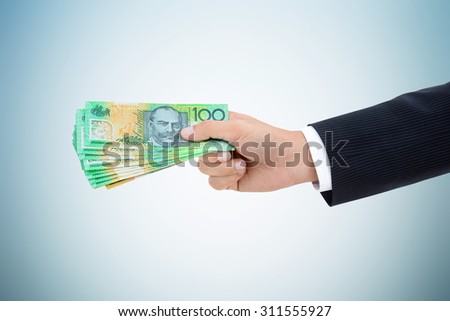 Businessman hand giving  money, Australian dollar (AUD) banknotes, on white gray background