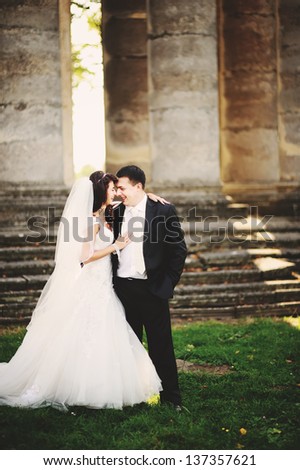 happy wedding couple next to columns of an old church