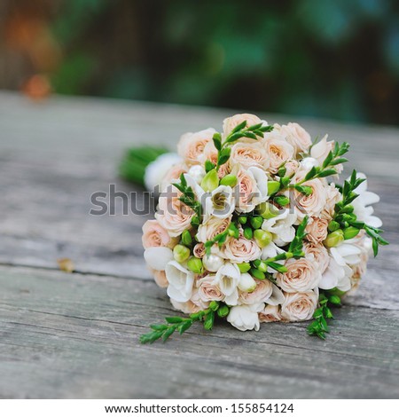 Bridal Bouquet of pink roses on wooden surface.