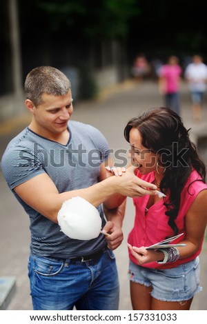 Young woman is biting a finger of her boyfriend, having fun.