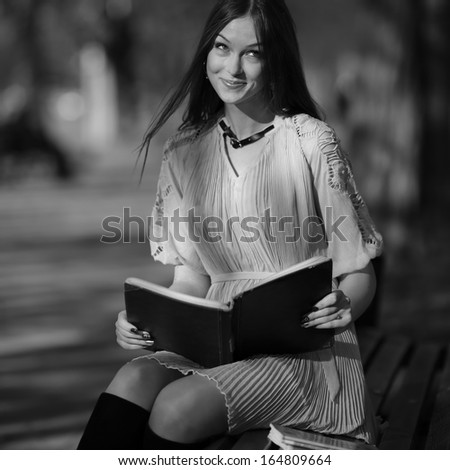 young beautiful woman reading book outside
