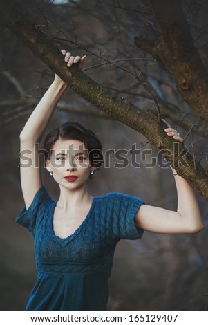 Young woman with retro coiffure posing in autumn garden.