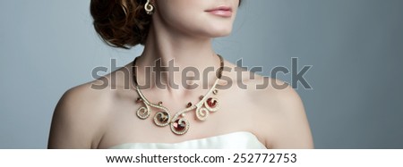 Young bride posing in studio, showing detail of necklace.