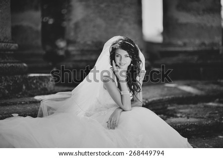 Young bride  posing  against an old church. Wedding picture in black and white.