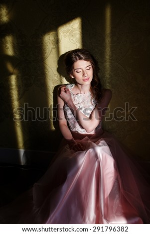 Teenage girl wearing fancy prom pink dress, posing on  school-leaving party.