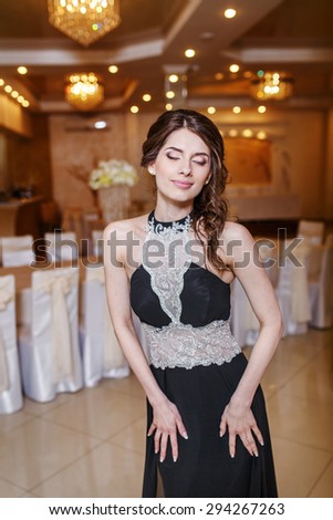 Portrait of young beautiful brunette woman wearing black prom dress.