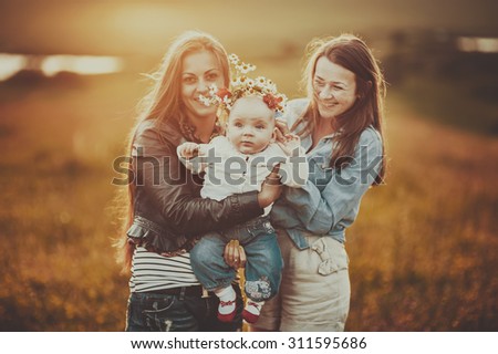 Happy family of mom sister and lovely daughter in sunset light.