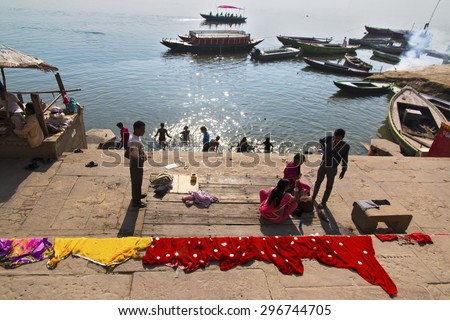 VARANASI, UTTAR PRADESH, INDIA - MAR 24, 2015: Local people doing their daily activities by the River Ganga at the Assi Ghat, including drying their clothes. Ghats of Varanasi serves many purposes.