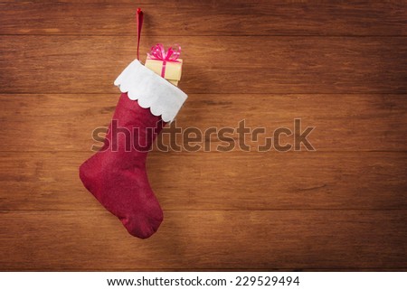 Christmas sock with yellow gift box on wooden background