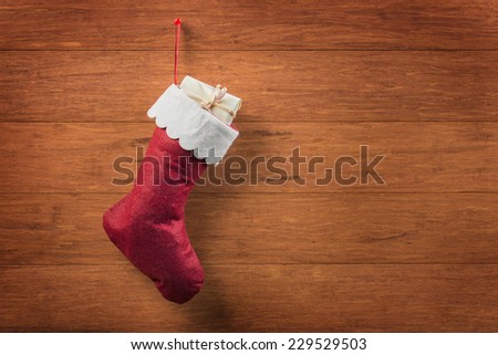 Christmas sock with light yellow gift box on wooden background
