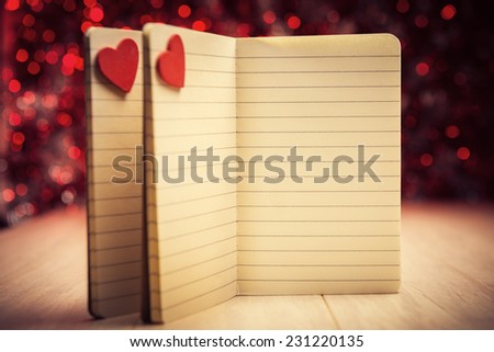 Open notebooks with red hearts against defocused lights, warm color toned