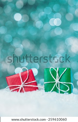 Red and green gift boxes in snow on abstract background