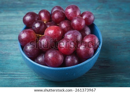 Grapes with water drops in blue plate on wooden table