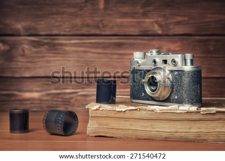 Vintage camera with 35mm film on old book over wooden background