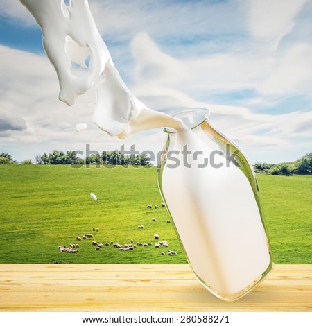 A bottle of milk on a table with a hill and the sheep in the background
