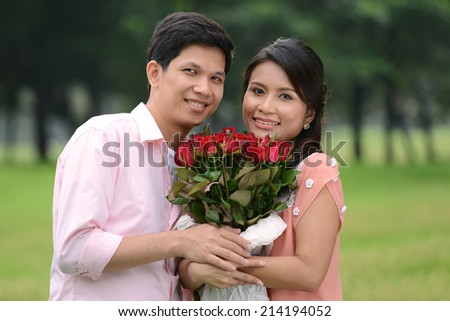 Young couple man and woman holding rose flower and smiling