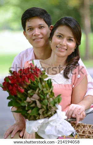 Young couple man and woman smiling in park with rose flower