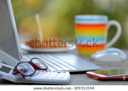 Breakfast coffee cup and laptop computer on business wooden table