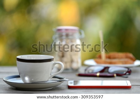 Breakfast coffee cup and smartphone mobile on business wooden table