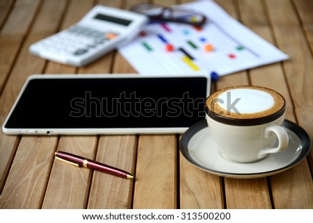 Coffee cup and tablet computer on business wooden table