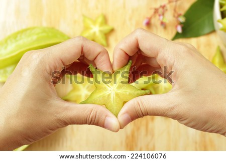 Girl hand in heart form love with sliced star fruit. Healthy concept.