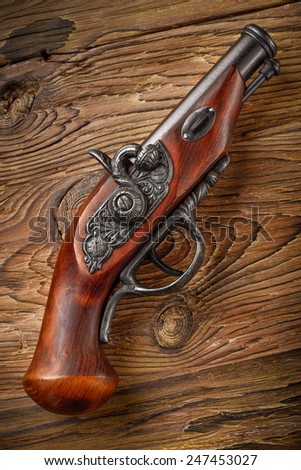 classic old pirate pistol on aged wood background
