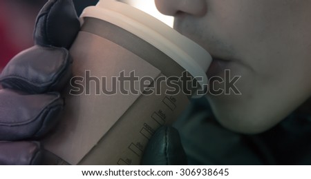 Unknow man hold paper cup of hot coffee with leather hand glove  and drink using mouth pastel tone like instagram