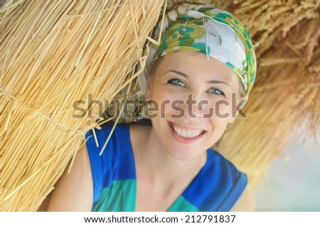 Sunny girl with a smile through architectural ornament. Female face portrait of a young woman with blue eyes, on a background of yellow wheat ears, happy smile, joy.