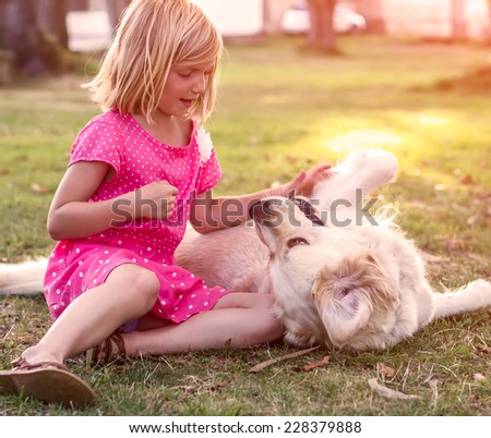 Young girl hugging golden retriever dog in the park
