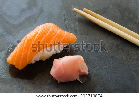 Salmon Sushi on slate texture. Sake Nigiri with chopstiks and  ginger directly on slate
