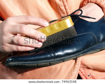 Hands cleaning or polishing black leather shoe