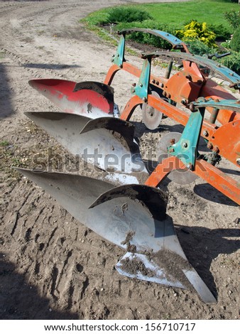 Tractor powered three furrow plow in country yard