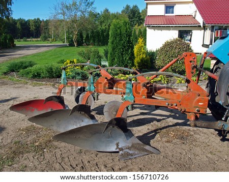 Tractor powered three furrow plow in country yard