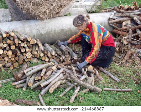 Woman work in country yard stacking firewood