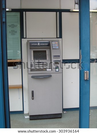 LIEPAJA, LATVIA - AUGUST 13, 2011: ATM or cash machine is located in small bank branch office behind closed glass doors.