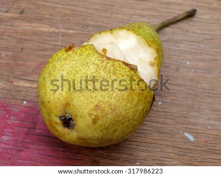 Partly eat big juicy pear on wooden table background close up.