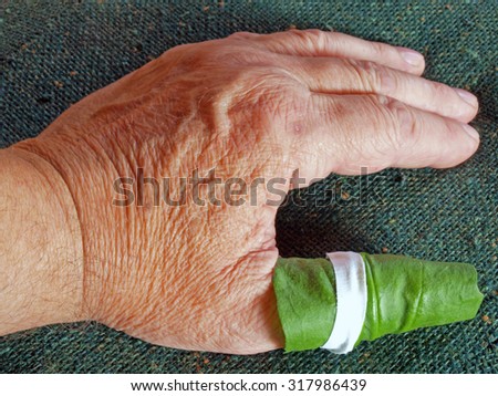 Medical herb greater plantain leaf as compress help for finger pain close up embedded with adhesive patch.
