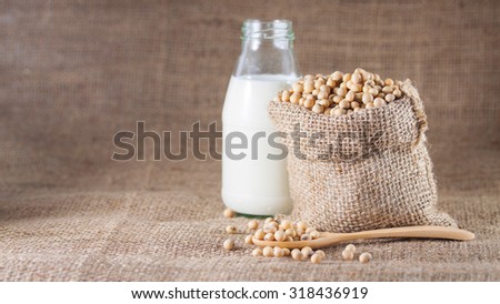 A bottle of soy milk and soy beans over textile background
