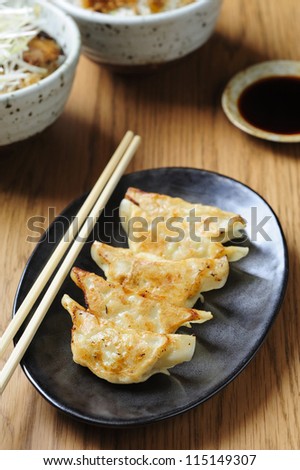 Pan-fried gyoza with dipping sauce and chopsticks
